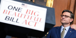 Mike Johnson, right, next to a podium with a sign that reads "One Big Beautiful Bill Act"