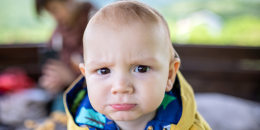 Close-up of adorable, funny little boy, in yellow jacket, with blond hair and brown eyes.