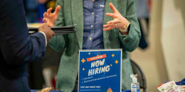 A "Now Hiring" sign at a job and resource fair.
