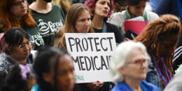 A woman holds a sign that reads "Protect Medicaid"