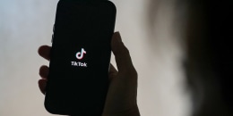 A person holds a phone with the TikTok logo.