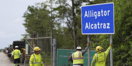 Workers install a sign reading "Alligator Alcatraz" at the entrance to a new migrant detention facility at Dade-Collier Training and Transition facility, Thursday, July 3, 2025, in Ochopee, Fla.