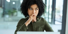  young businesswoman looking thoughtful while using a laptop in a modern office 