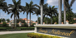 A sign is seen near the entrance to the Trump National Doral golf resort, many palm trees in the background near resort buildings