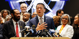 Gene Wu speaks at a podium surrounded by other people