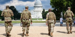 National Guard soldiers walk outside, the U.S. Capitol is seen in the distance