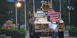 A protester is blown around in the rain as members of the D.C. National Guard take shelter in their vehicle outside Union Station in Washington