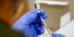 A healthcare worker fills a syringe.