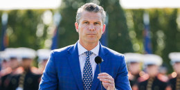 Pete Hegseth stands at a podium outside