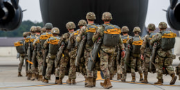 Soldiers walk into an airplane parked on the tarmac outside