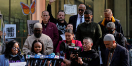 Protesters hold signs that read "Faith over fear"