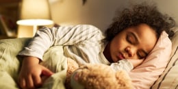 Little boy sleeping in bed with toy