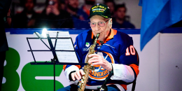 Dominick Critelli plays the clarinet while seated in front of sheet music on a stand, on the ice
