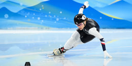 Kristen Santos-Griswold skates low on the ice, one hand touching the ground