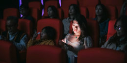 woman reading phone message during cinema movie show time in the dark ignoring and disturbing other audience around her