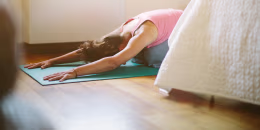 image: Mid adult woman in yoga position on bedroom floor