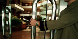 Image: A doorman opening the door to a luxury hotel foyer, 25 June 2002