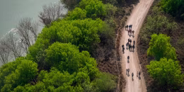 Migrants walk on a dirt road along the Rio Grande in Mission, Texas, on March 23, 2021, after crossing the U.S.-Mexico border.