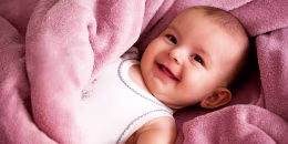 Portrait of baby girl smiling wrapped in a soft blanket