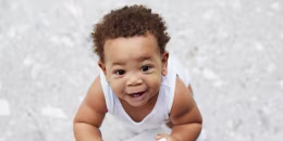 Overhead view of smiling baby boy standing in kitchen