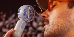 a man holding a portable fan
