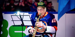 Dominick Critelli plays the clarinet while seated in front of sheet music on a stand, on the ice