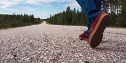 Finland, Lapland, feet of man walking on empty country road