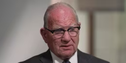 Image: A man in glasses and a suit.
