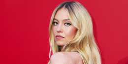Sydney Sweeney poses against a red backdrop