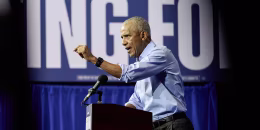 Former President Obama standing at a lectern during a political rally.