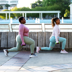 Two African-American woman doing lunges in city park