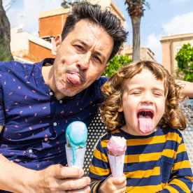 Happy father and son sitting on bench enjoying an ice cream