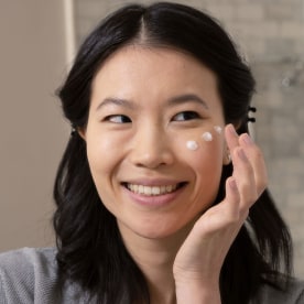 Woman using cream on her cheek