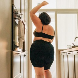 Rear view of young voluptuous woman with hand raised dancing in kitchen