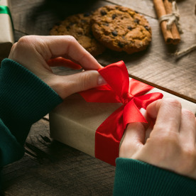 someone adding a red bow to a gift