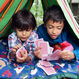 Mixed Race boys playing card game in blanket fort
