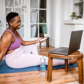 Woman working out at home while watching online yoga class.