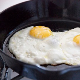 Eggs fry in a cast iron skillet.