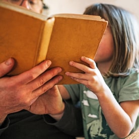 A father reads a book to his daughter