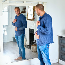 Man checking himself in bathroom mirror and touching tummy