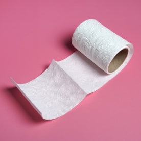White toilet paper roll with  on pink background