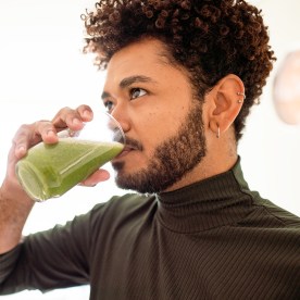 Young man drinking a healthy green smoothie at home.