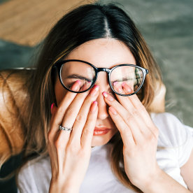 Young woman rubs her eyes after using glasses.
