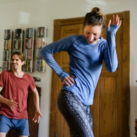 A young couple working out doing some aerobic exercises at home together.