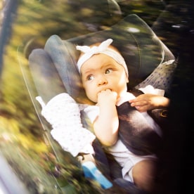 Little baby fastened in car seat.