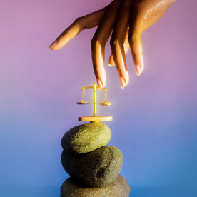 Photo of a hand touching a scale balanced on rocks symbolizing libra 2024.