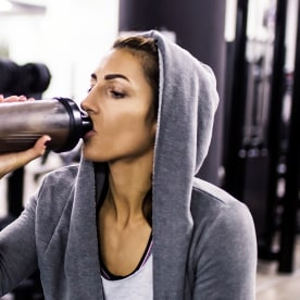 Woman bodybuilder drinking protein shake at gym