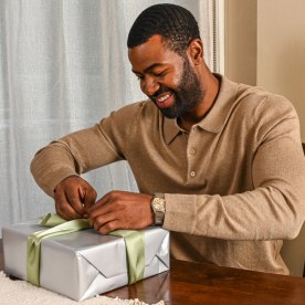 a man opening a gift wrapped in silver paper