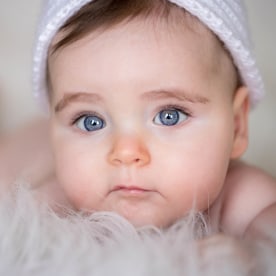 Portrait of cute baby girl lying on bed