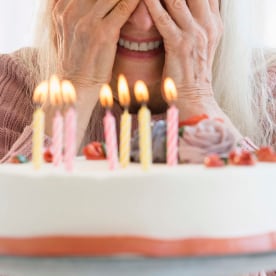 Senior woman peeking at candles on birthday cake